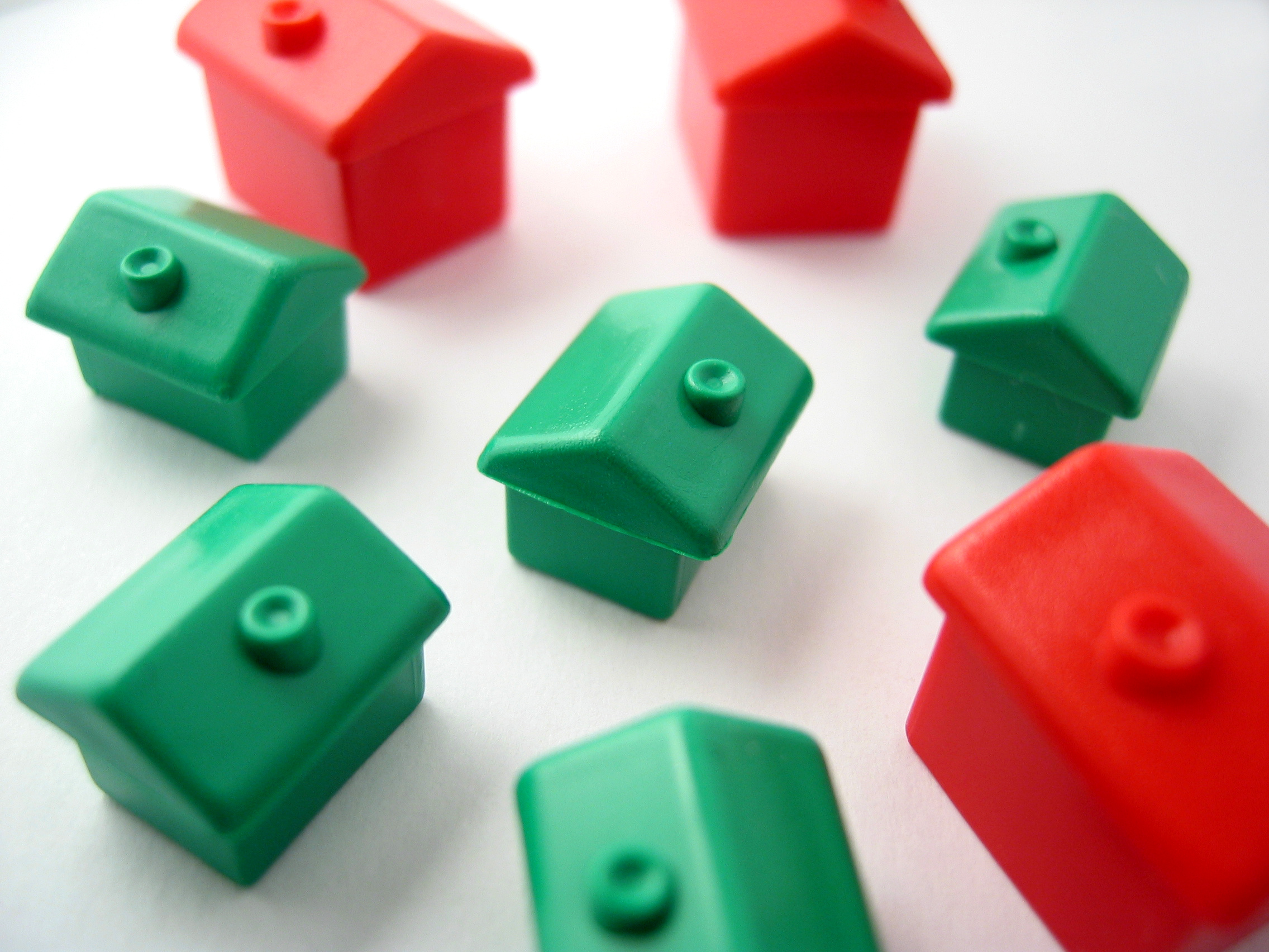 Miniature red and green houses against a white background.