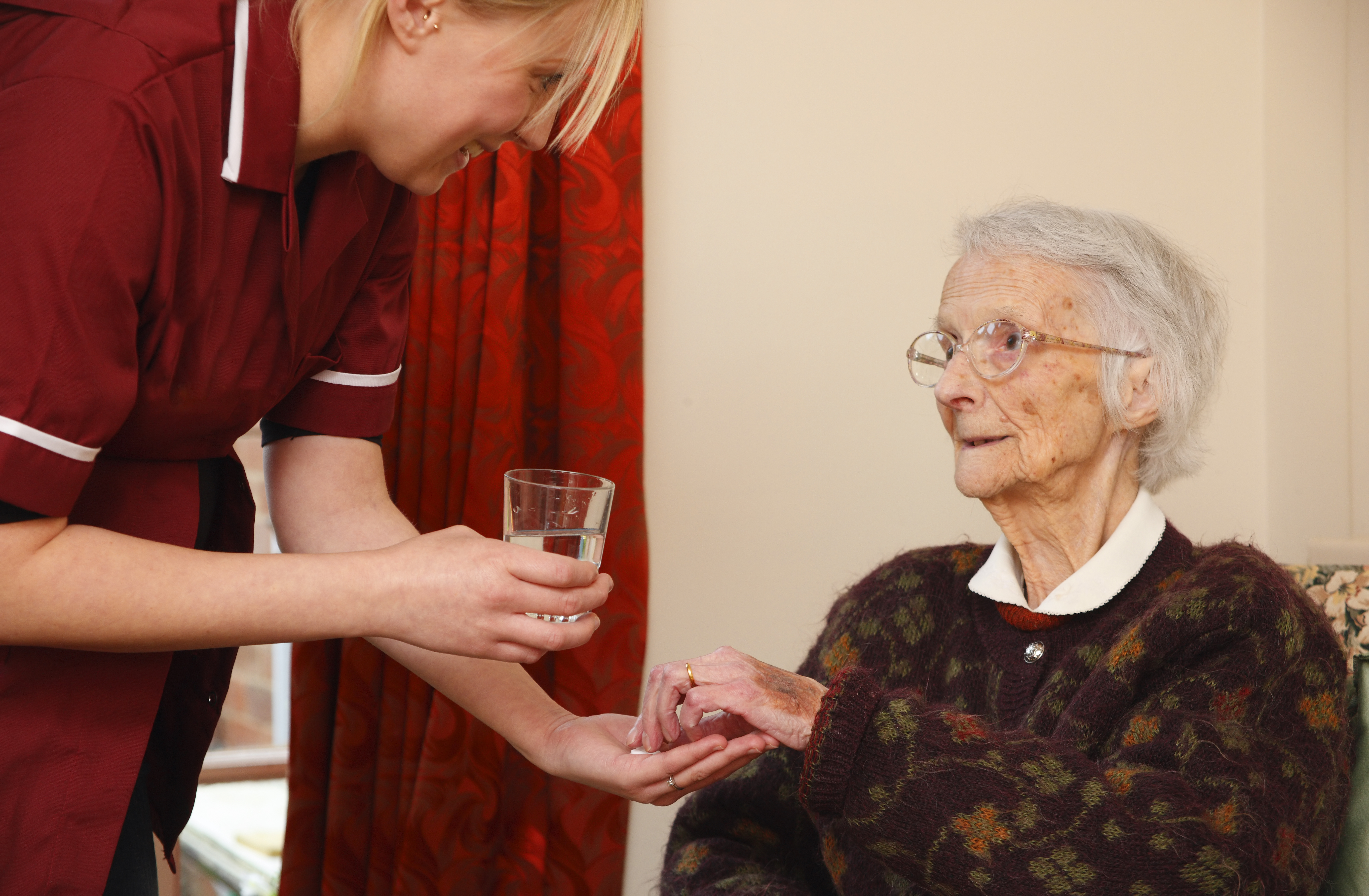 pregnant carer giving pills and medication to her patient