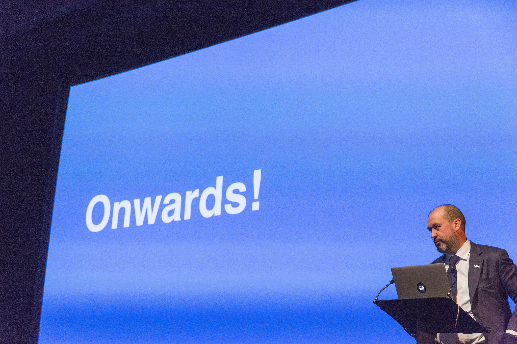 Mike Bracken, former Executive Director Digital for the UK Government, on a stage with the word 'Onwards' in the background. 